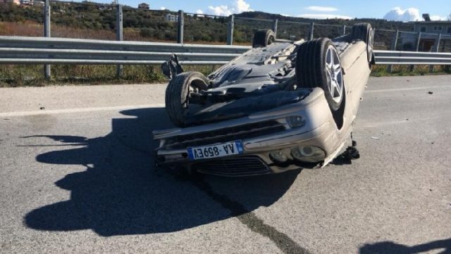 Përplasen dy automjete, njëri përmbyset në rrugë